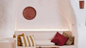 A cozy room with a white sofa, a wooden coffee table, and a wall-mounted plate. - The Monachil Caves: "Lap" (Monachil)