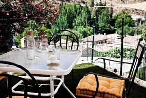 Ein Tisch mit Glasplatte, Stühle, einem Kissen und einer Flasche.