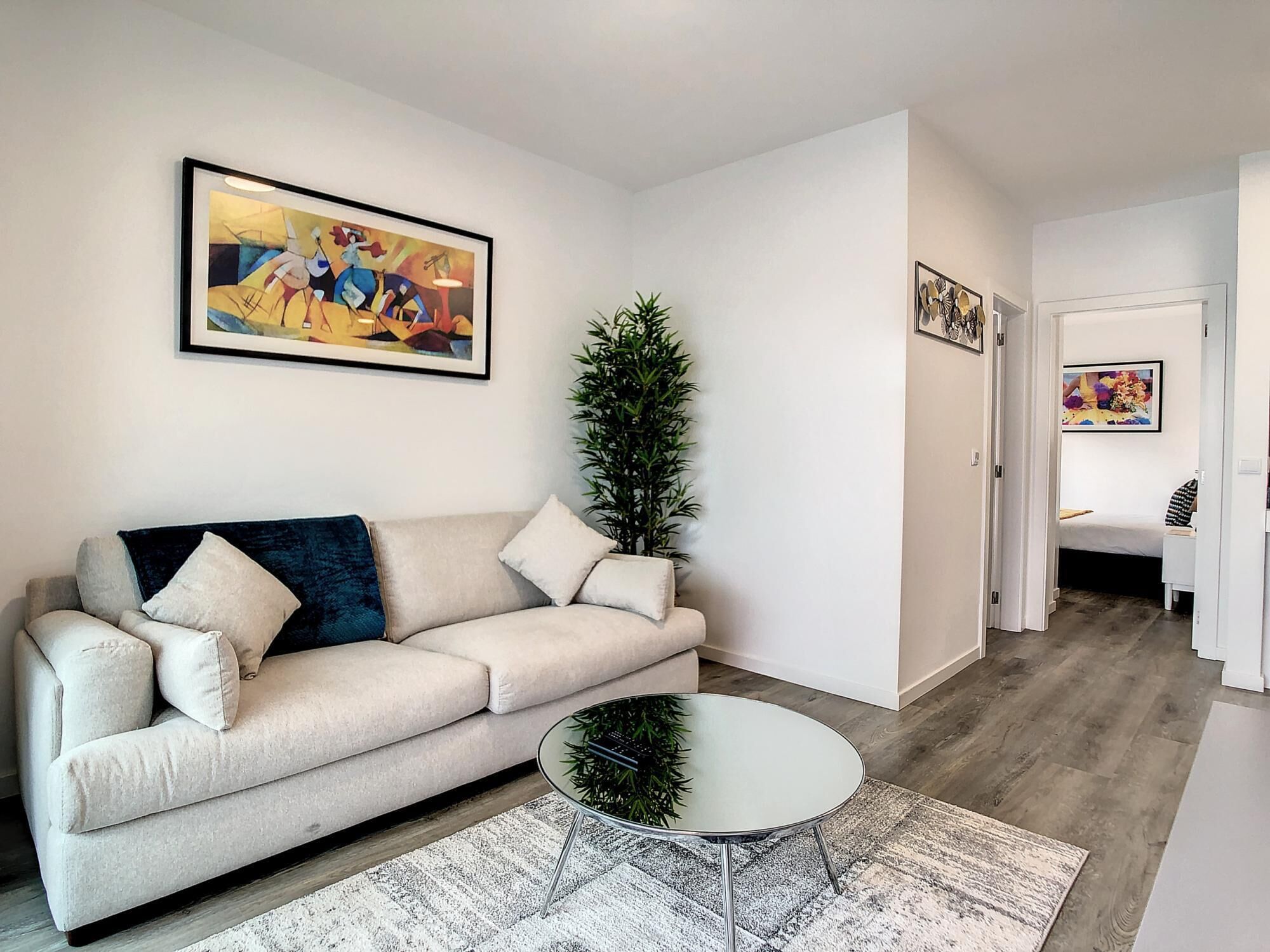 A living room with a beige sofa, a round coffee table, and a potted plant.