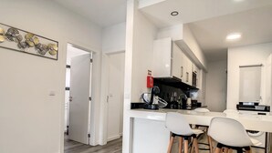 Cozinha moderna com armários brancos, coifa preta e um balcão com banquetas.