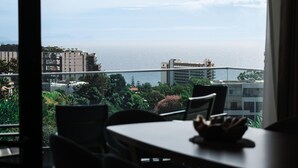 Ein Zimmer mit Meerblick und einer Brücke. Im Vordergrund stehen ein Tisch und Stühle.