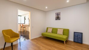 A living room with a green sofa, a yellow chair, and a wooden floor. - Magn lia Apartment by Atlantic Holiday (Funchal)