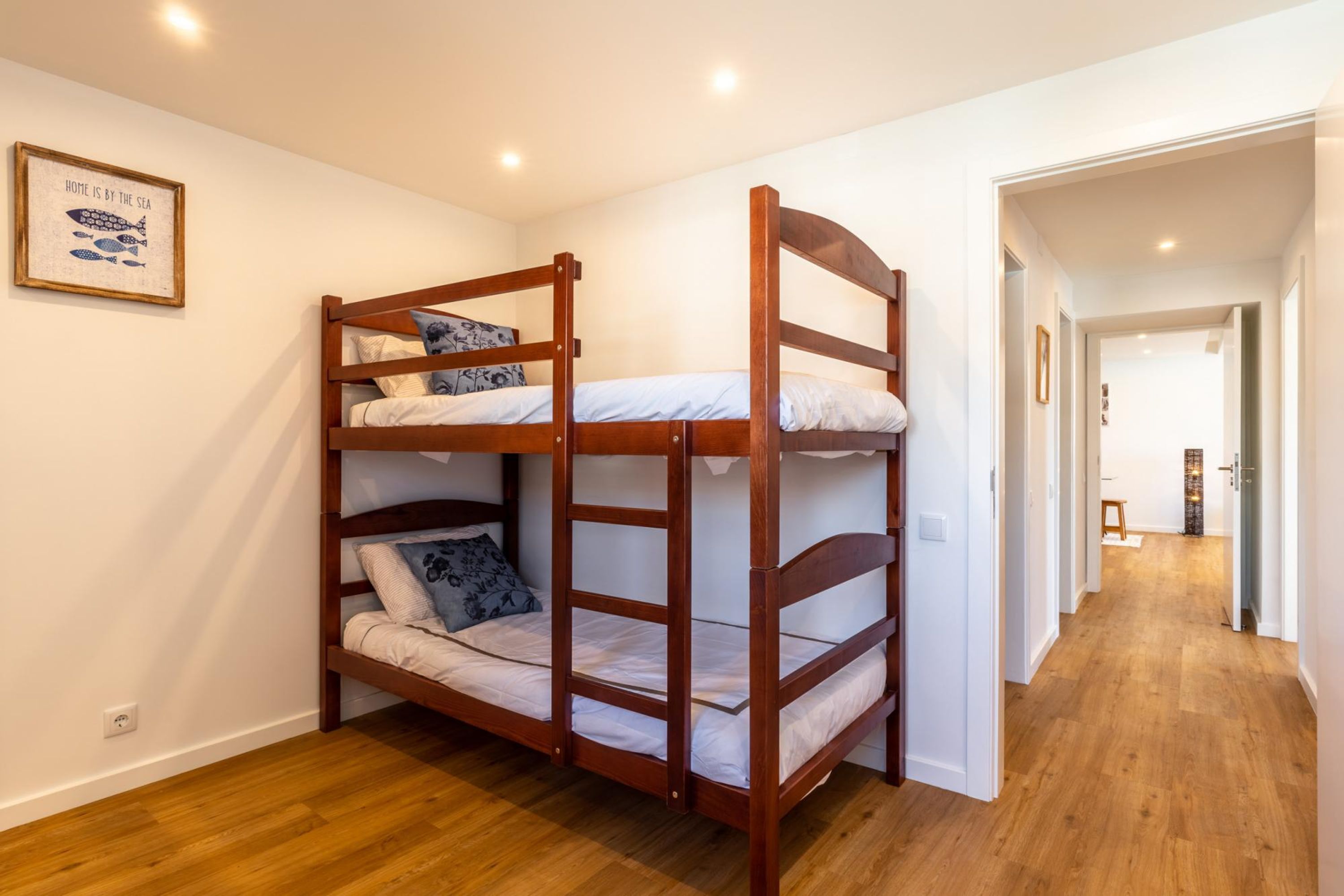 Camera con letto a castello, strutture in legno, biancheria bianca e una citazione incorniciata al muro.