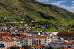 A hillside town with terraced houses and a prominent building with a red roof.