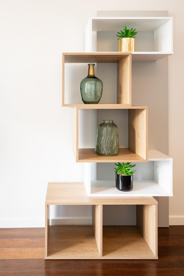 Una estantería de madera escalonada con tres repisas, cada una con una planta y un florero.