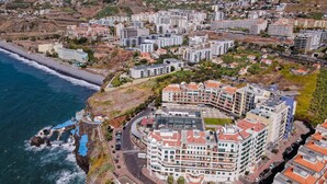 A coastal cityscape with modern residential buildings, a curved road, and a beach. - Centromar Bella Vista by Atlantic Holiday (Funchal)