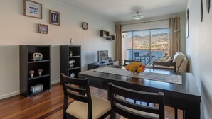 A dining area with a wooden table, chairs, and a view of a mountainous landscape through large windows. - Centromar Residence Ocean View by Atlantic Holiday (Funchal)