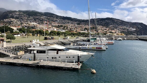 Un port de plaisance avec des bateaux amarrés, un quai où est accosté un bateau nommé « Sea Borne », et une vue sur la ville en arrière-plan.