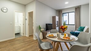 Un salon moderne comprenant un coin repas, un téléviseur et une fenêtre avec des rideaux.
