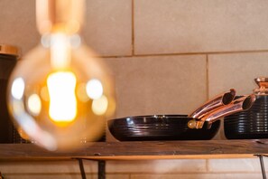 A kitchen counter with a black frying pan, a copper pot, and a glass jar. - Stone House Vista II by Atlantic Holiday (São Vicente)