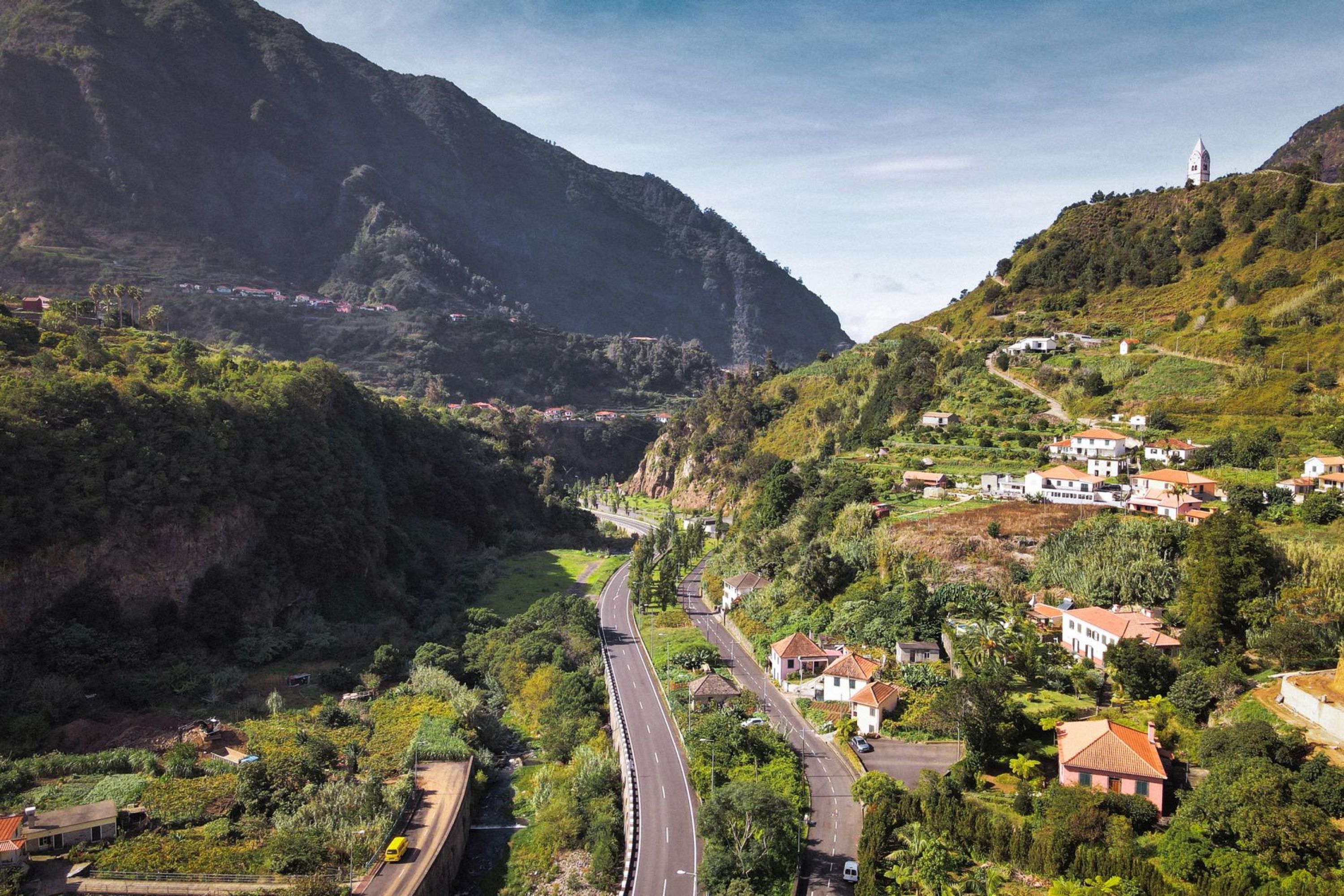 Un paysage montagneux avec une route sinueuse, des maisons et une église située sur une colline.