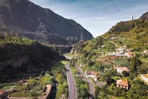 A mountainous landscape with a winding road, houses, and a church on a hill. - Stone House Vista by Atlantic Holiday (São Vicente)