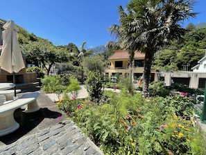 A garden with a stone bench, a hammock, and a house with a red roof. - Stone House Vista by Atlantic Holiday (São Vicente)