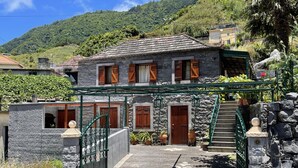 A stone house with a tiled roof, wooden shutters, and a green gate. - Stone House Vista by Atlantic Holiday (São Vicente)