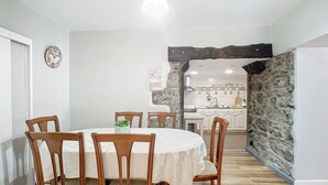 A dining area with a round table, wooden chairs, and a clock on the wall. - Stone House Vista by Atlantic Holiday (São Vicente)