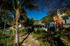 A garden pathway leading to a building with a thatched roof, surrounded by lush greenery and palm trees. - Stone House Vista by Atlantic Holiday (São Vicente)