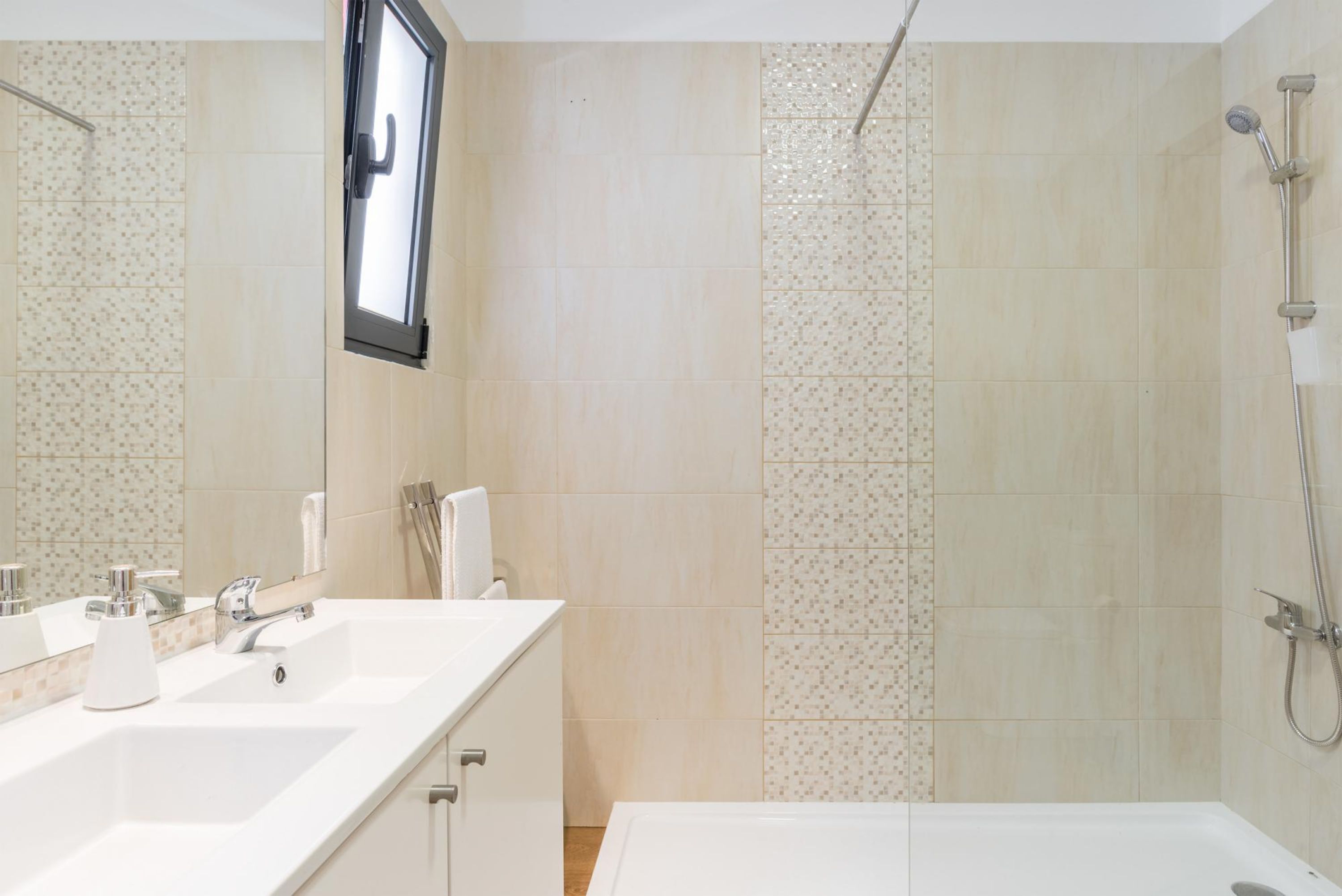 A modern bathroom with two sinks, a mirror, and a shower area.