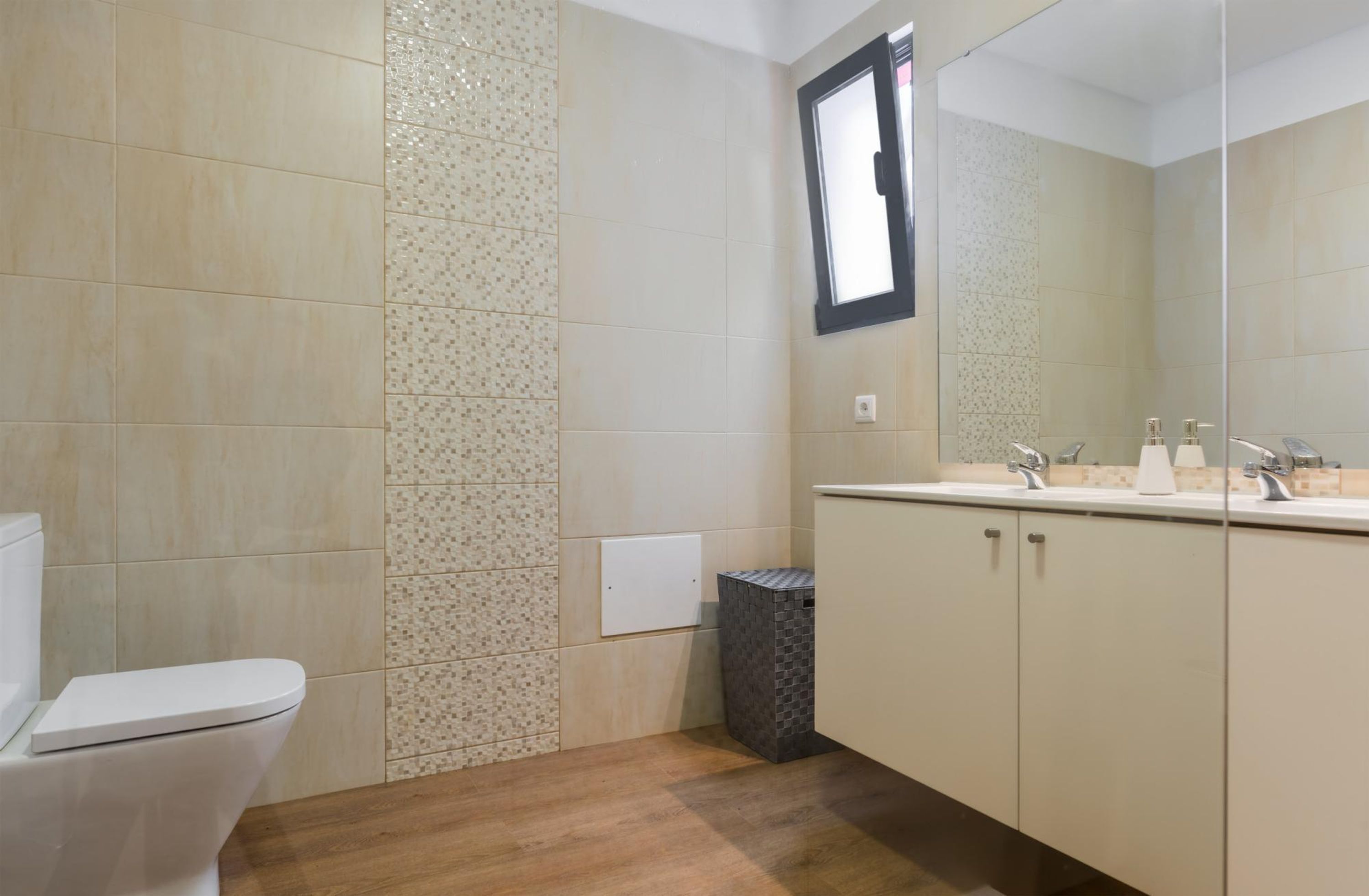 Baño con inodoro, lavabo con espejo y cubo de basura.