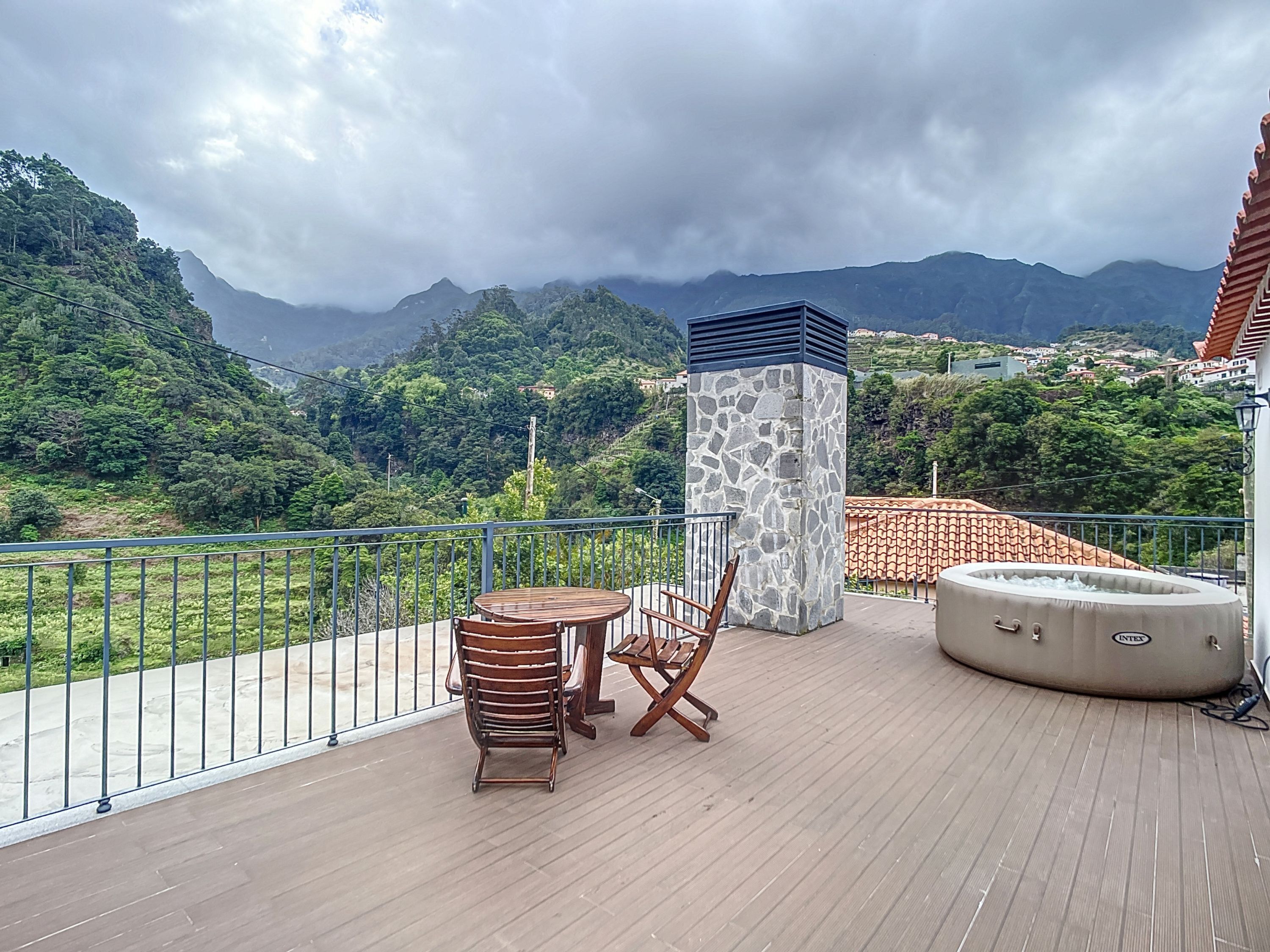 Ein Balkon mit Tisch und Stühlen, einer Steinsäule und einem Whirlpool.