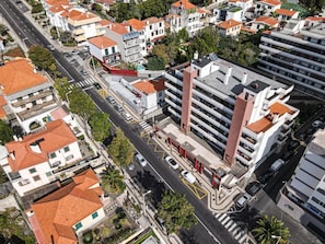 An aerial view of a residential area with modern and traditional buildings, a main road, and a pedestrian crossing.