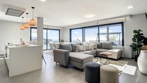Un salon moderne avec un canapé, des poufs et un îlot de cuisine.
