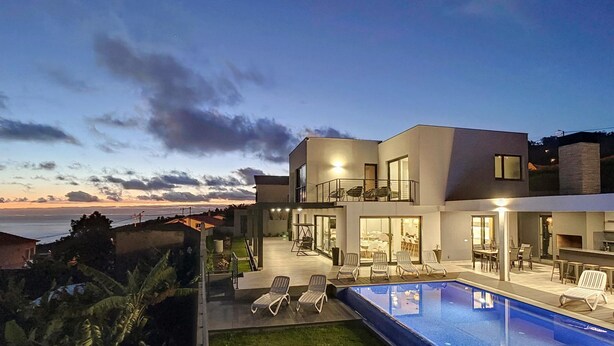 Une maison moderne dotée d’une piscine, d’un espace salon extérieur et offrant une vue sur l’océan.