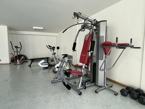 Un gimnasio con equipo de ejercicio variado, incluyendo una cinta de correr, una elíptica y máquinas de pesas.