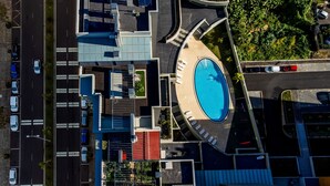 An aerial view of a modern building with a central swimming pool, multiple parking areas, and a landscaped garden. - Terrace Apartment by Atlantic Holiday (Funchal)