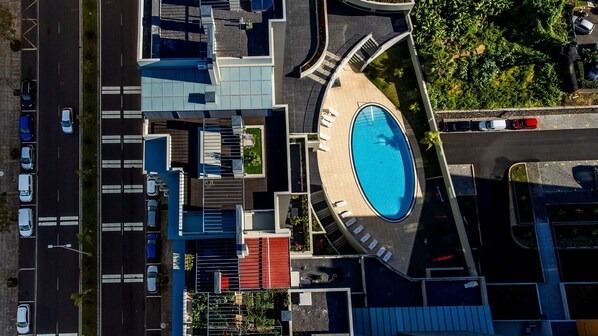 An aerial view of a modern building with a central swimming pool, multiple parking areas, and a landscaped garden. - Terrace Apartment by Atlantic Holiday (Funchal)