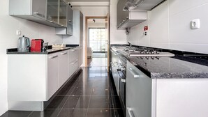 A modern kitchen with stainless steel appliances, white cabinetry, and a black countertop. - Terrace Apartment by Atlantic Holiday (Funchal)