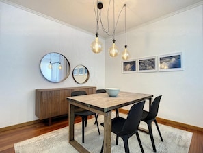 A dining area with a wooden table, black chairs, a wooden cabinet, and a round mirror. - Terrace Apartment by Atlantic Holiday (Funchal)