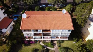 Un edificio de varios pisos con techo de tejas rojas, antenas parabólicas y balcones.