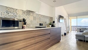 Una cocina moderna con un salpicadero estampado, un microondas integrado y una isla de madera con cajones.