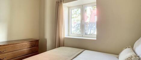 Un dormitorio con una cama, un aparador de madera y una ventana con cortinas.