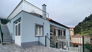 Um edifício de dois andares com varanda, fachada de pedra e guarda-corpo de metal.