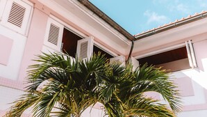 Un edifici amb façana rosa, una porta ben visible i una finestra amb persianes.