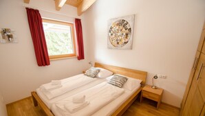 Een tweepersoonsbed met witte lakens, een houten hoofdbord en een klein nachtkastje met een lamp.