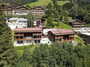Un ensemble d’immeubles modernes à plusieurs étages, dotés de balcons, entouré d’une végétation luxuriante et d’un paysage vallonné.