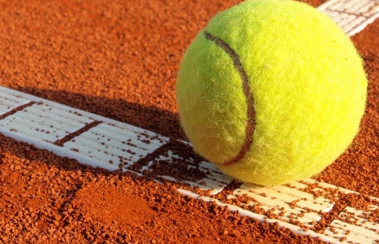 A tennis ball on a clay court with white boundary lines.