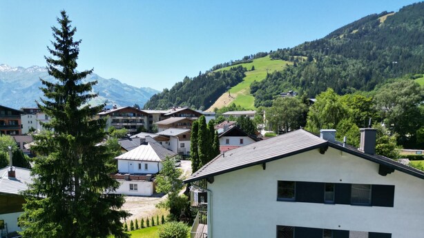 A modern building with a flat roof and multiple windows, surrounded by lush greenery and a mountainous backdrop. - 5 Seasons House Zell am See - TOP 1 Summer Card (Zell am See)
