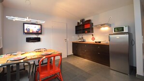 A compact kitchen with a dining table, chairs, a TV, a microwave, and a refrigerator. - 5 Seasons House Zell am See - TOP 1 Summer Card (Zell am See)