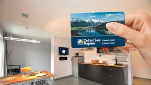 Moderni keittiö, jossa on ruokailutila, taulutelevisio ja Zell am Seen kesäaktiviteettikortti.