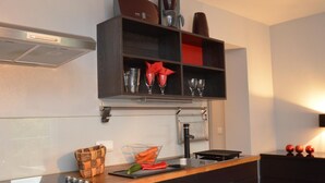 A kitchen with a black countertop, a basket, a cutting board with vegetables, and a coffee machine on a shelf. - 5 Seasons House Zell am See - TOP 4 Summer Card (Zell am See)