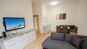 A modern living room with a flat-screen TV, a grey sofa, a small coffee table, and a white cabinet. - Apartment Cityxpress TOP 7 - Zell am See (Zell am See)