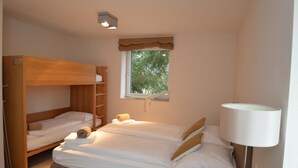 A bedroom with a bunk bed, a single bed, a window with a view of trees, and a bedside lamp. - 5 Seasons House Zell am See - TOP 5 Summer Card (Zell am See)