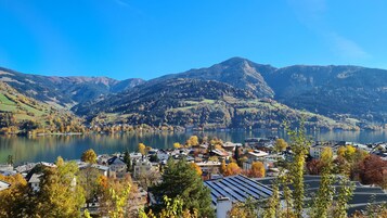 A lakeside town with a view of mountains, houses with solar panels, and autumn foliage.