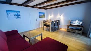 Una sala de estar moderna con una mesa de comedor de madera, sofás rojos y un televisor sobre un mueble de madera.