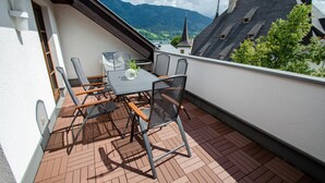 Un balcon avec une table et des chaises, donnant sur un paysage montagneux.