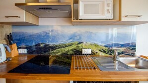 A kitchen with a wooden countertop, a stainless steel sink, a microwave, and a stove.