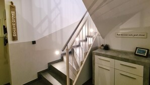A staircase with a glass panel on the wall, a sign that reads "Hello Winter," and a cabinet with drawers. - Post Residence Apartments 11A Sauna Near Skilift (Zell am See)